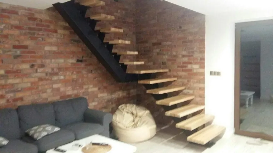 Freitragende Holztreppe vor Ziegelwand – Referenzprojekt