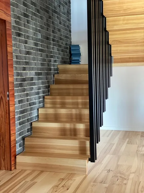 Geschlossene Holztreppe mit schwarzem Stabgeländer – Referenzprojekt